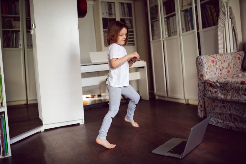 Gimnastyka przedszkolaka przed laptopem dziewczynka robiąca ćwiczenia dla dzieci przed laptopem