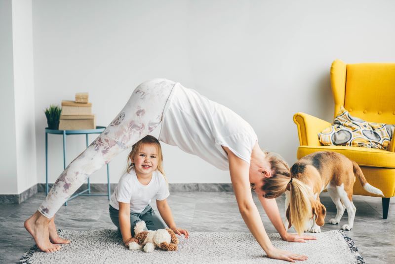 mama robiąca ćwiczenia na brzuch w domu razem z dzieckiem i psem