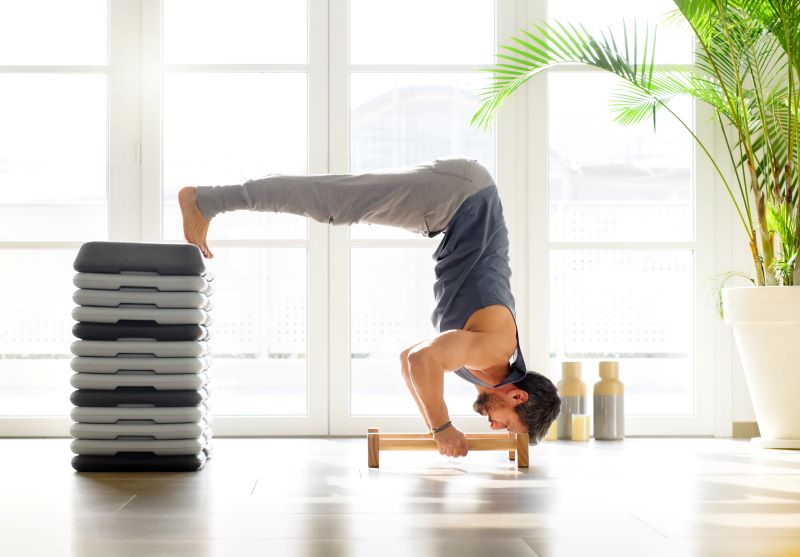 męzczyzna robiący kalisteniczny  trening w domu z paraletkami